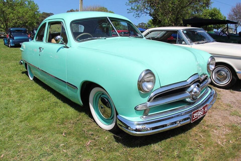 Commons identifies a 1949 Ford Custom Tudor. It matches the year, Custom series and two-door sedan body; the file description lists both six and V-8 engines, so this photographed car's V-8 and original U.S.-market specification are not independently proven.