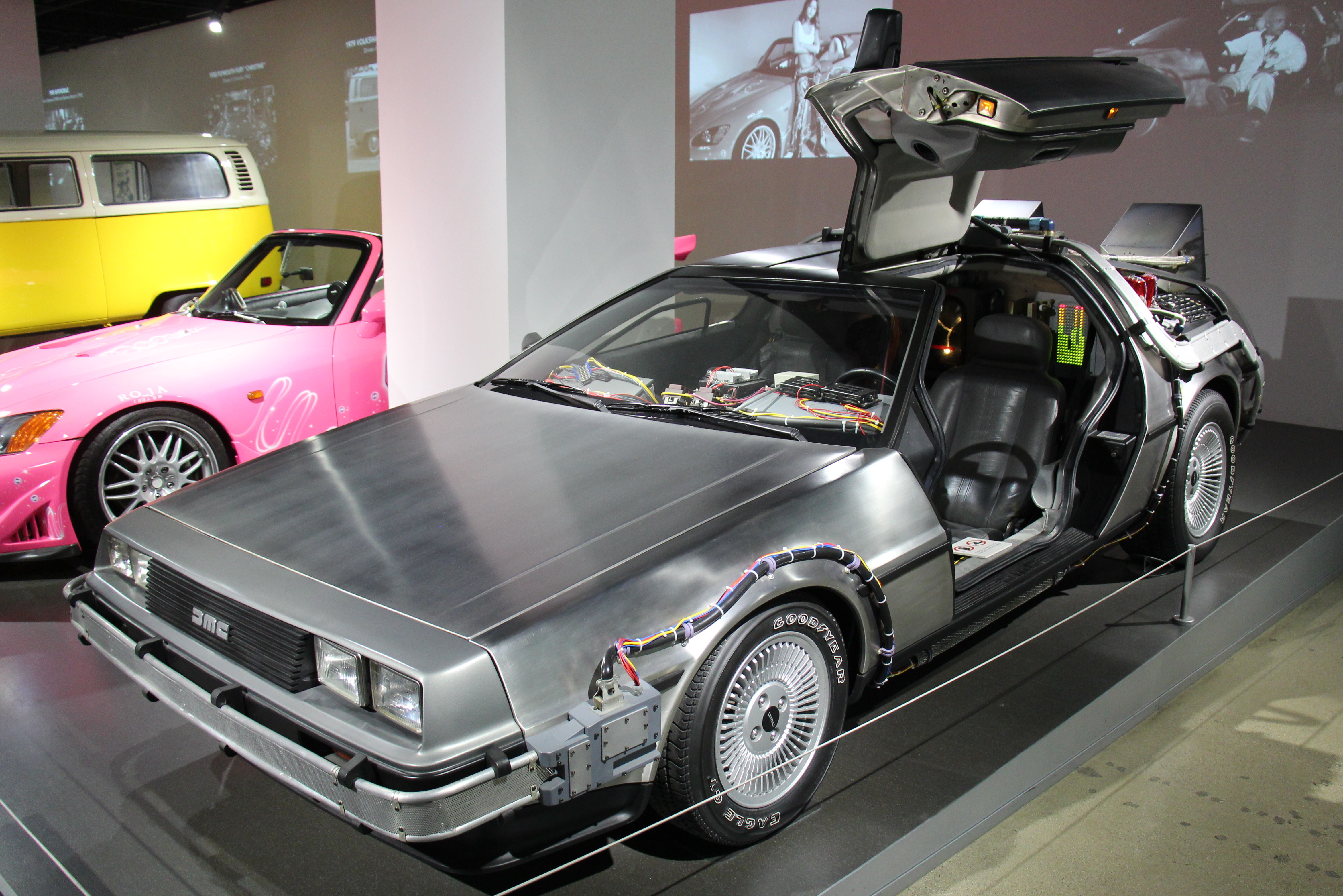 Michael J. Fox’s actual Back to the Future Hero Car, a restored stainless-steel 1981 De Lorean time-machine prop displayed front-left at the Petersen; no registration is visible.