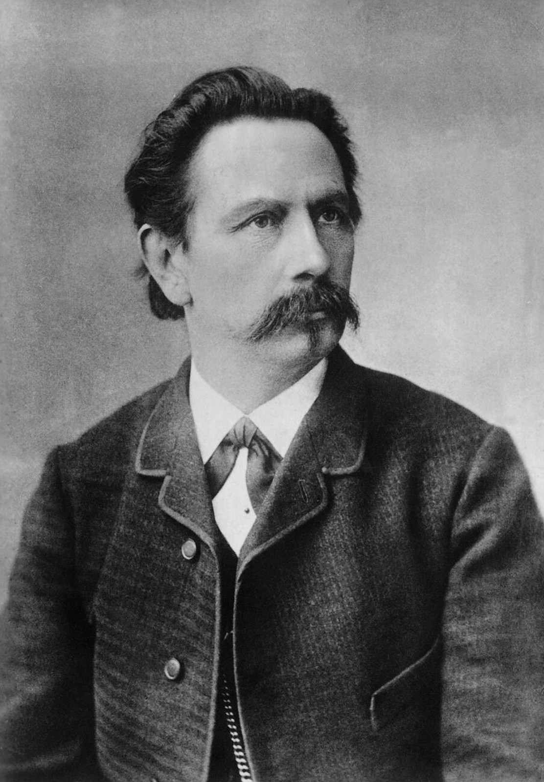 Black-and-white circa-1889 portrait of Carl Benz in a dark jacket, light shirt and tie.
