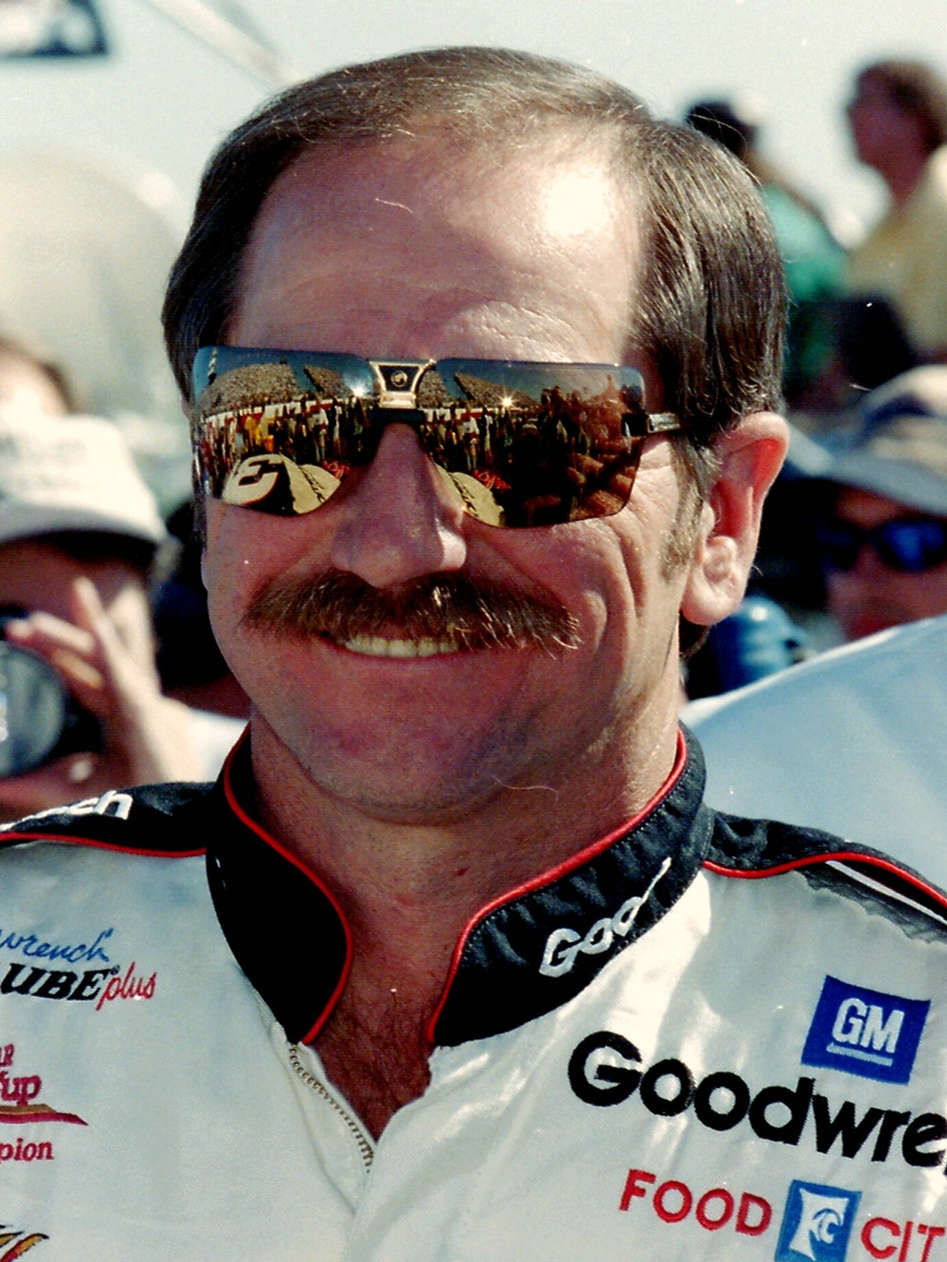 Dale Earnhardt smiling in a racing suit and mirrored sunglasses.