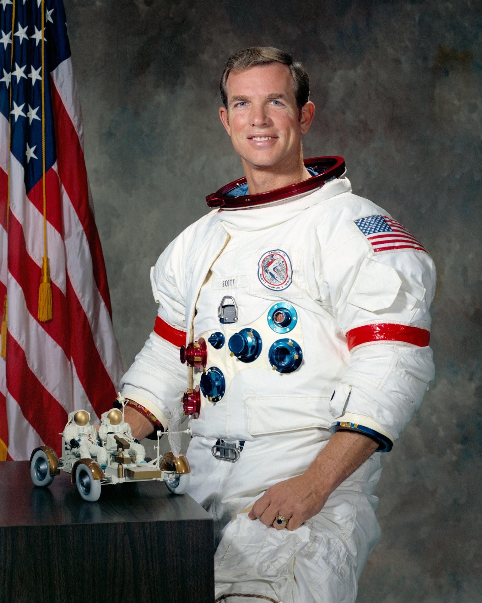 Official 1971 NASA portrait of Apollo 15 commander David Scott in a white spacesuit in front of a United States flag.