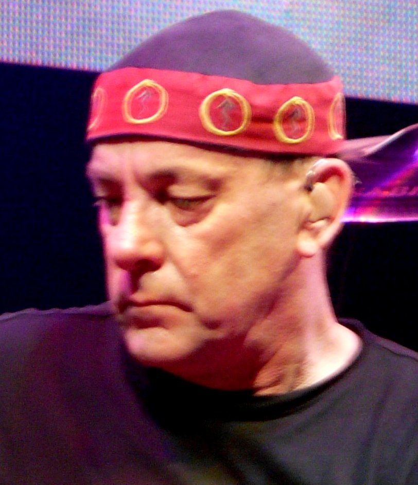 Neil Peart performing with Rush in 2008, wearing a red and black cap.